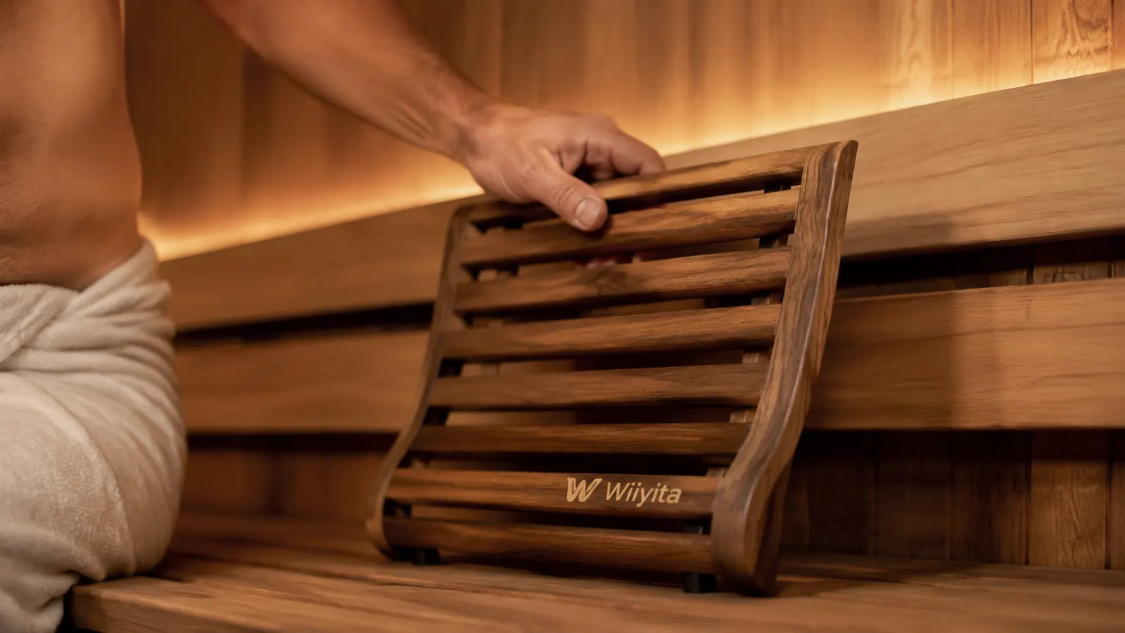 Hand repositioning the wooden sauna backrest lower on the bench to fit a taller person's back